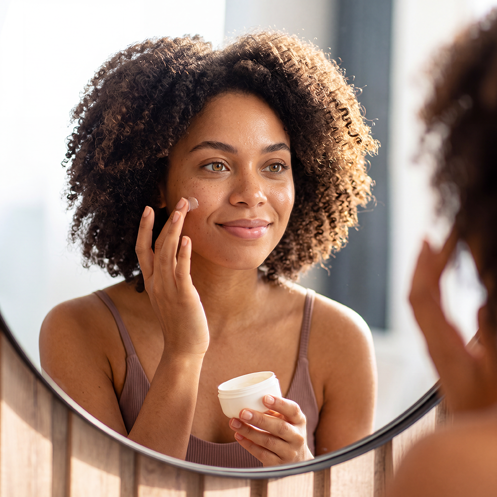 Femme devant un miroir qui passe une crème sur la joue