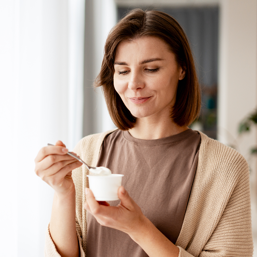 Une femme mange un yaourt