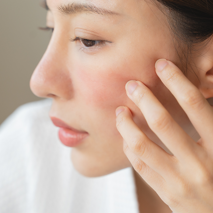Femme de profil avec un visage lisse qui pose ses doigts sur sa joue