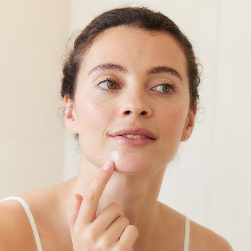 Femme posant un pimple patch sur le menton