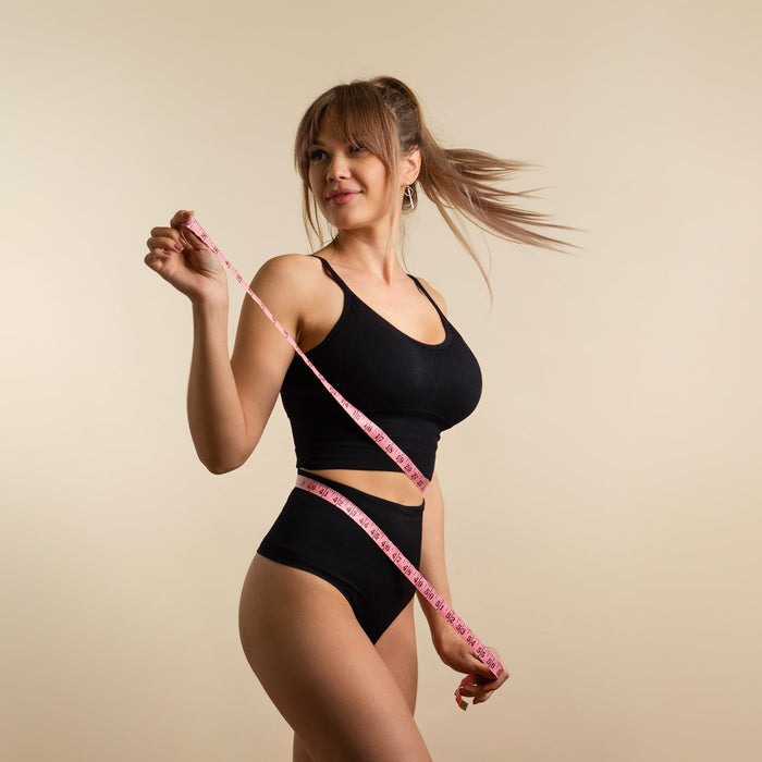 Femme en tenue de sport qui mesure son tour de taille